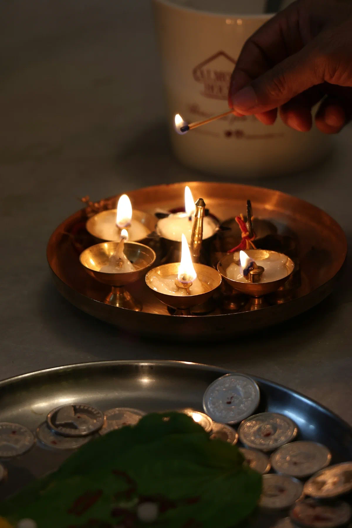 Five lit brass diyas arranged on a dark plate
