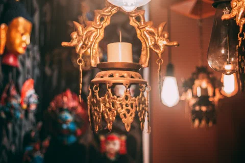 A hanging brass temple lamp lit against stone
