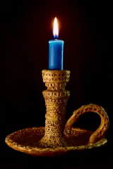 An ornate brass candle holder with a lit candle